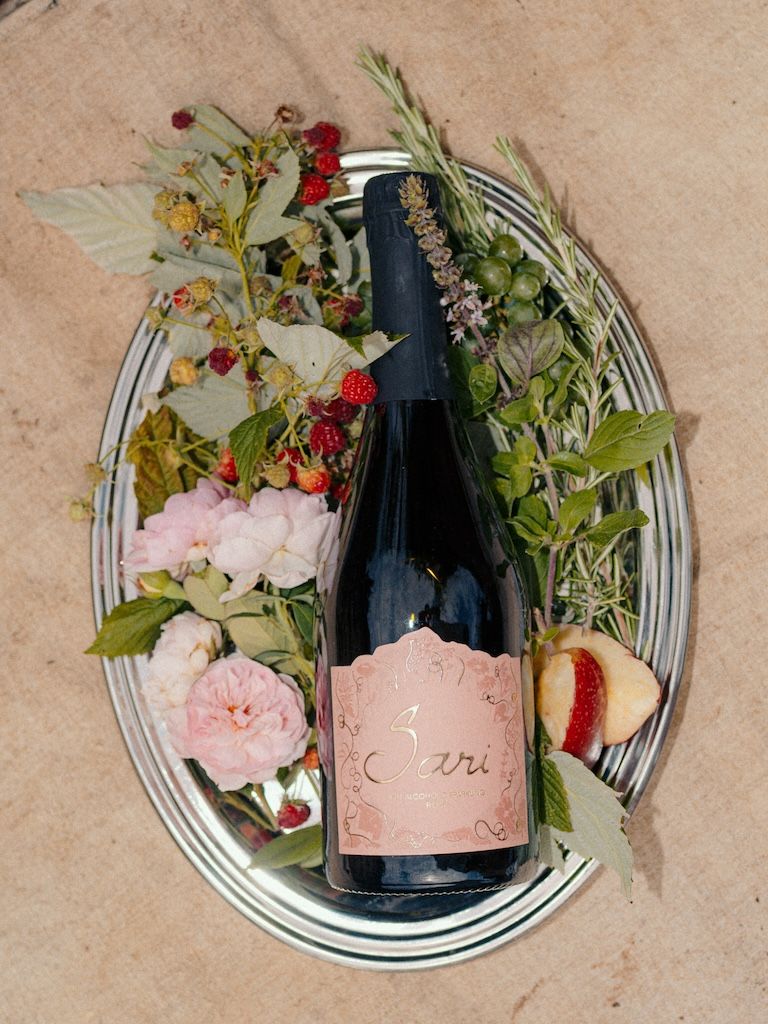Bottle of Sari Rosé on a silver tray with raspberries, roses and fresh herbs