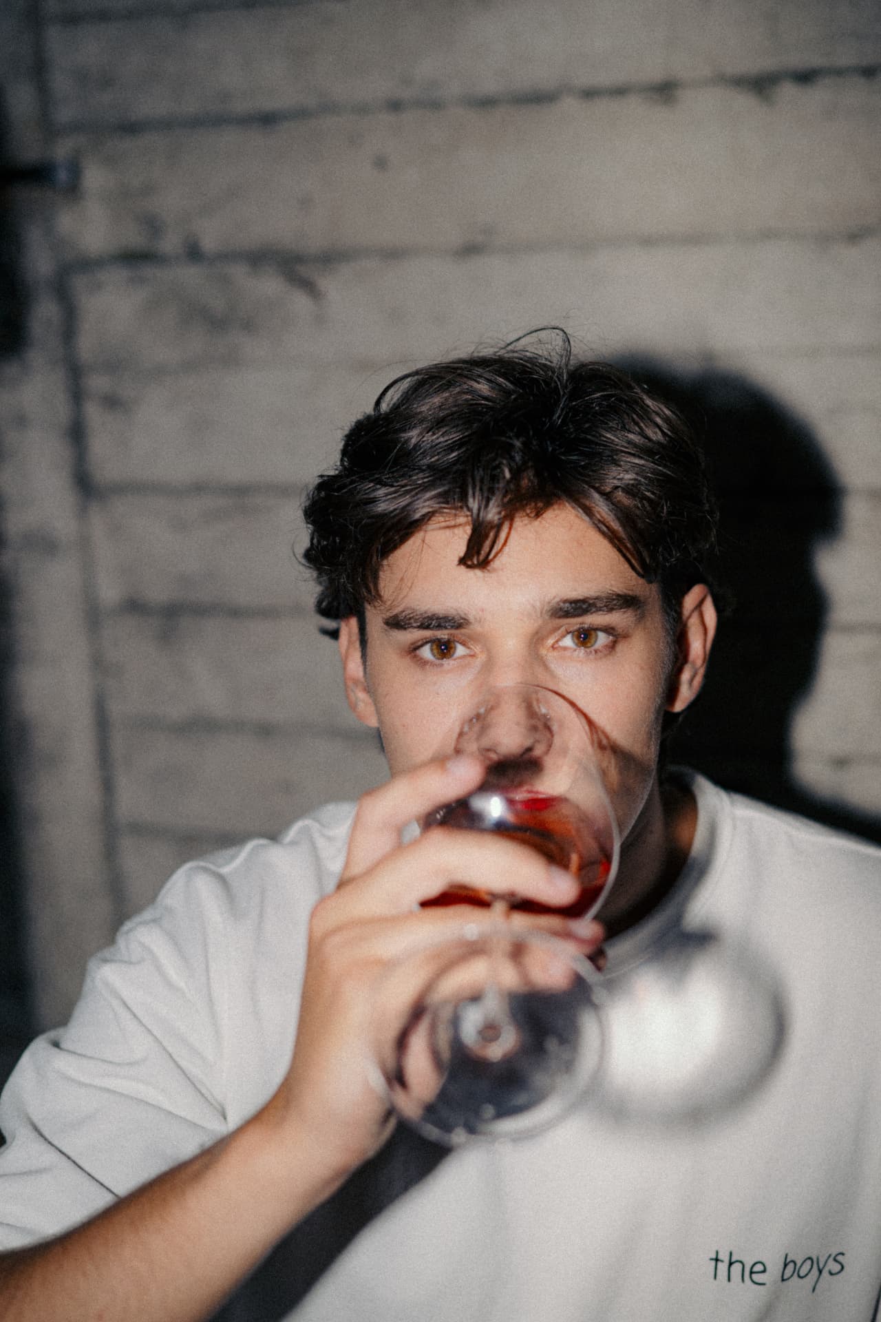 Man tasting a glass of Sari against a white brick wall