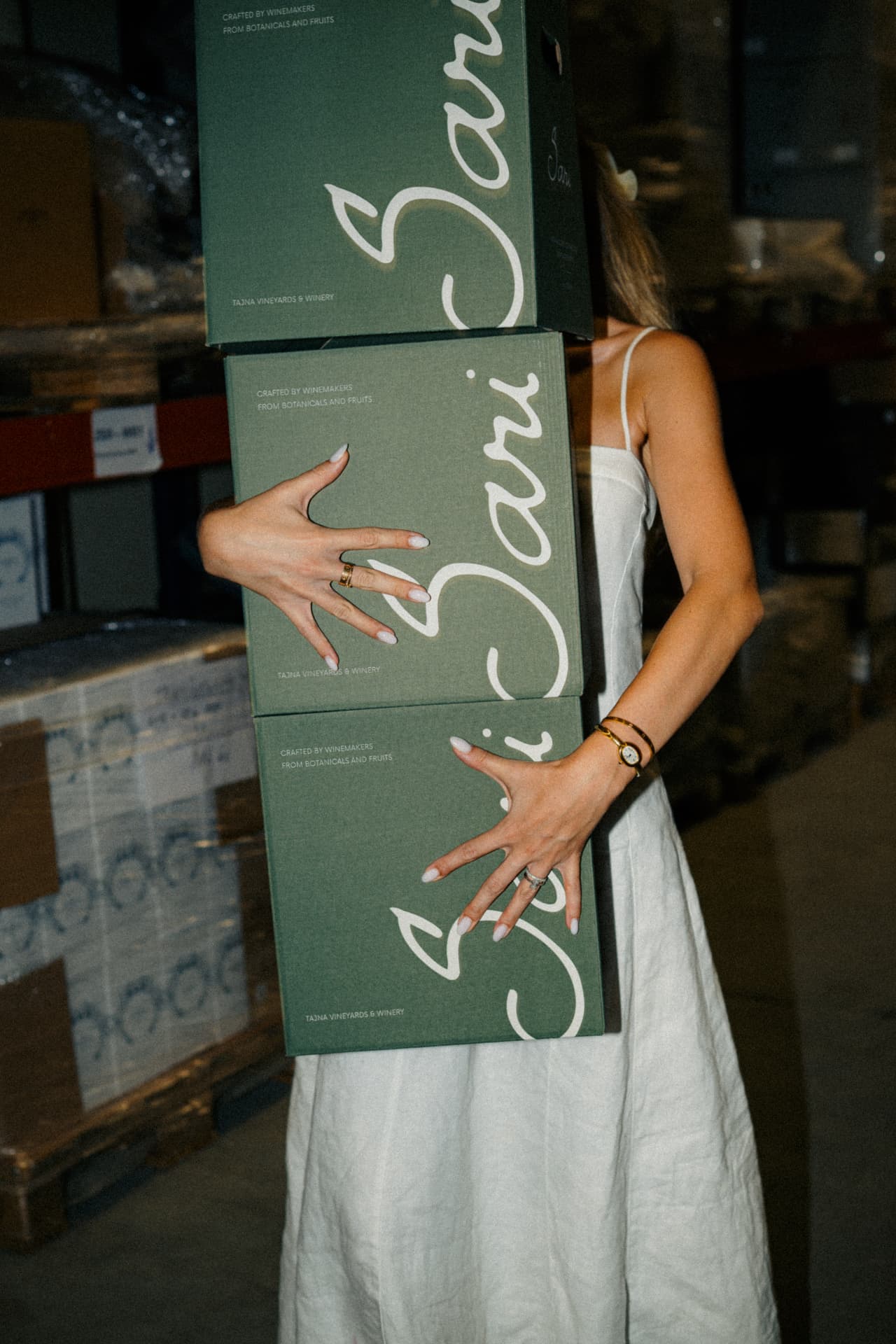 Woman carrying a stack of green Sari gift boxes in the winery warehouse