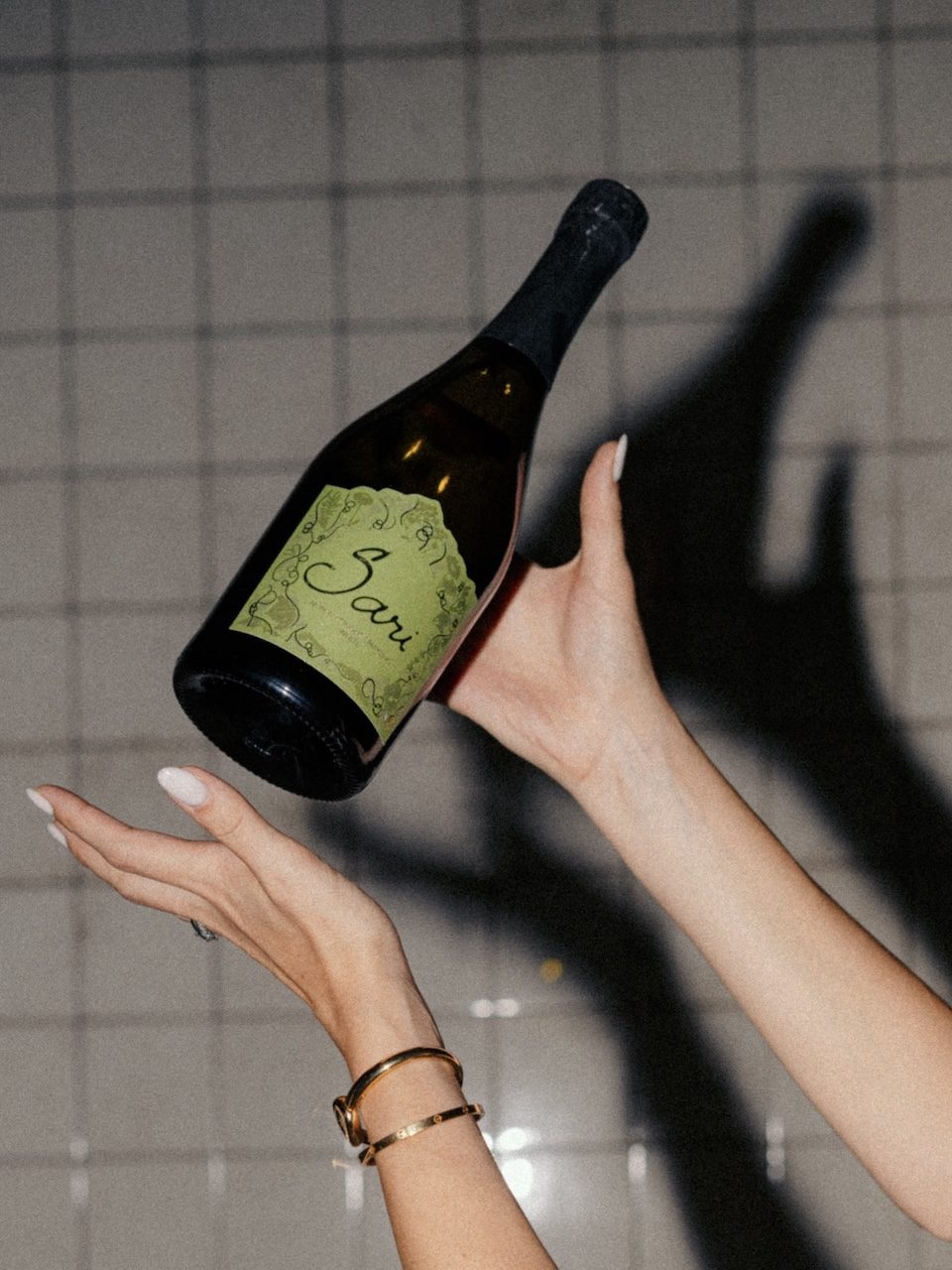 Hands holding a bottle of Sari White against a tiled wall